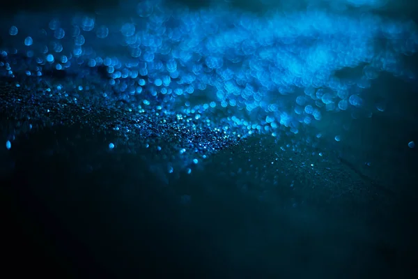 Mavi parıltılı doku. Siyah arka planda serpiştirilmiş tohumlar. Işıldayan etki. Bokeh. Bulanık arkaplan