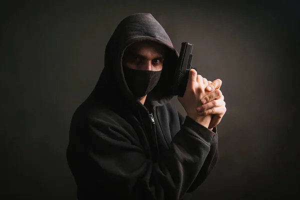 Gangster Kapturze Masce Trzyma Broń Rękach Ciemnym Tle Bandyta Celuje — Zdjęcie stockowe