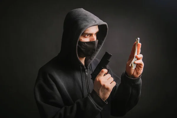Gangster Kapturze Masce Trzyma Broń Rękach Ciemnym Tle Bierze Pieniądze — Zdjęcie stockowe