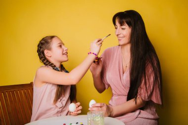 Anne ve kızı Paskalya için yumurta boyuyor. İnançlı kadın ve çocuk birlikte oynaşıyor. Hıristiyan ailesi