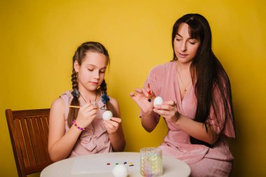 Anne ve kızı Paskalya için yumurta boyuyor. İnançlı bir kadın ve bir çocuk dini bir tatile hazırlanıyor. Hıristiyan ailesi