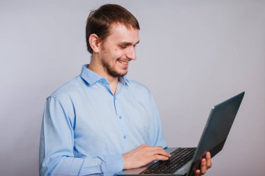 Mavi gömlekli bir adam beyaz arka planda dizüstü bilgisayar tutuyor. Erkek ofis çalışanı.