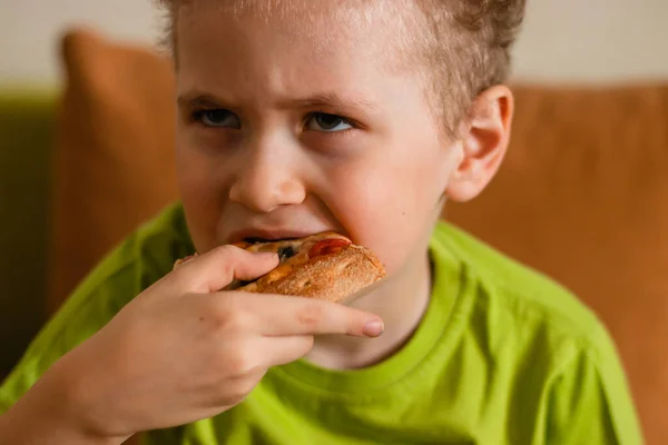 Kıvırcık Saçlı Yeşil Tişörtlü Bir Çocuk Pizzadan Bir Isırık Alır — Stok fotoğraf