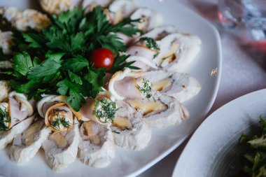 Parti atıştırması. Beyaz tabakta peynirli dilimlenmiş et. Maydanoz