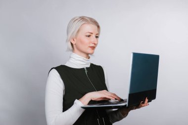 Elinde dizüstü bilgisayarı olan zeki bir kadın klavyeye yazı yazıyor. Beyaz arka planda sarışın.