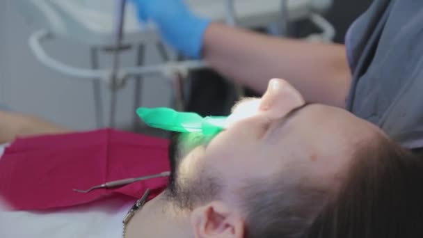 Стоматолог осмотрит зубы пациента специальным зубным зеркалом. Парень на приеме у дантиста. лечение зубов — стоковое видео