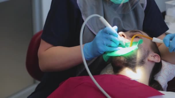 Il dentista esamina i denti dei pazienti con uno specchio dentale speciale. Il tizio all'appuntamento dal dentista. cure dentali — Video Stock