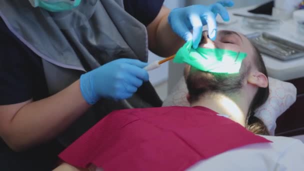 Tandläkaren tar bort patientens saliv med ett speciellt dentalt instrument. Killen på tandläkarmötet. tandvård — Stockvideo
