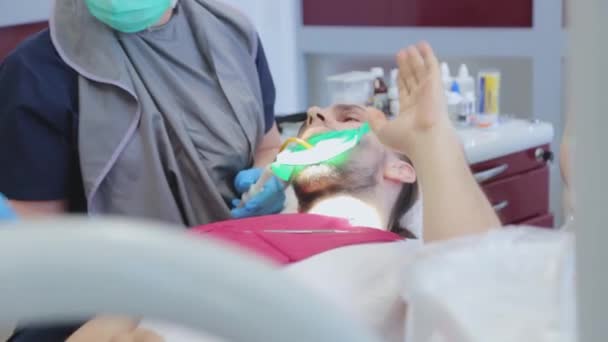 Der Zahnarzt entnimmt dem Patienten den Speichel mit einem speziellen zahnärztlichen Instrument. Kerl beim Zahnarzttermin. Zahnbehandlung — Stockvideo