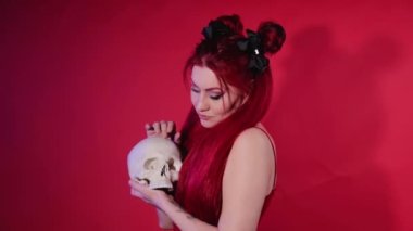 Gayri resmi görünümlü genç bir kadın bir insan kafatasını kucaklıyor. Rockçı kız merhumla konuşuyor. Cadılar ritüeli.