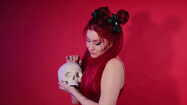 A young woman of informal appearance hugs a human skull. The rocker girl talks to the deceased. Witches ritual. — Stock Video