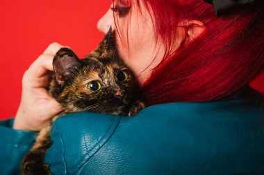 Gayri resmi görünümlü genç bir kadın kaplumbağa kabuğundan bir kediye sarılıyor. Rockçı kız evcil hayvanını okşuyor. Bir kızın bir kediye olan aşkı