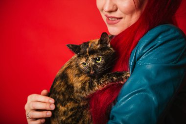 Gayri resmi görünümlü genç bir kadın kaplumbağa kabuğundan bir kediye sarılıyor. Rockçı kız evcil hayvanını okşuyor. Bir kızın bir kediye olan aşkı