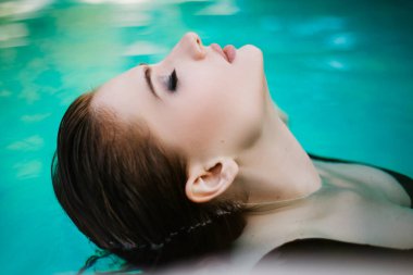 Mavi havuzda ıslak saçlı güzel bir kız. Evde dinlenin. Bahçedeki çerçeve havuzu