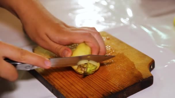 Ženská ruka krájí zelené papriky na kostky na dřevěné desce. — Stock video