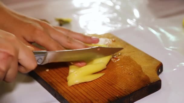 Een vrouwenhand snijdt groene paprika 's in blokjes op een houten plank. — Stockvideo