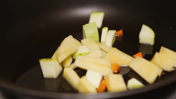 Dobj cukkinit és répát egy fekete serpenyőbe. Főzőzöldség otthon. — Stock videók
