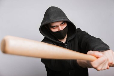 Siyah kapüşonlu maskeli bir haydut, kot pantolon ve beyaz arka planda bir yarasa. Suçlu tehdit ediyor.