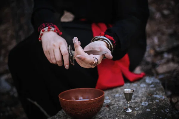 用刀割断他的胳膊 并在牛奶中添加血液 特写女性的手参与了巫术仪式 巫婆正在石头上举行仪式 — 图库照片