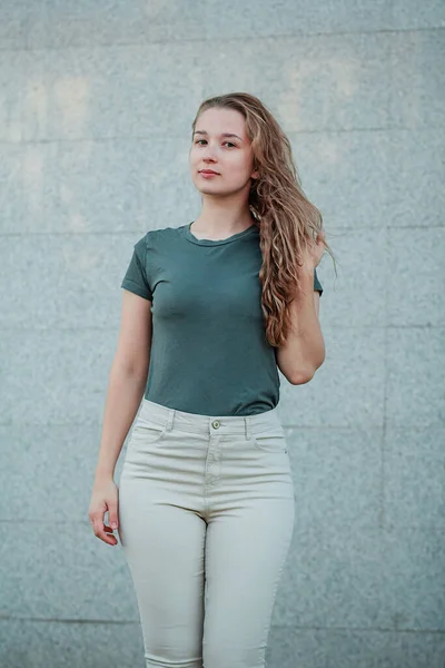 Uma Jovem Mulher Uma Camiseta Turquesa Escura Está Contra Uma — Fotografia de Stock