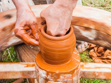 Bir çömlekçinin elleri, çemberin üzerinde toprak kavanozu yaratıyor.