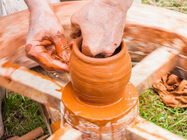 Bir çömlekçinin elleri, çemberin üzerinde toprak kavanozu yaratıyor.