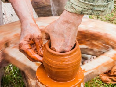 Bir çömlekçinin elleri, çemberin üzerinde toprak kavanozu yaratıyor.