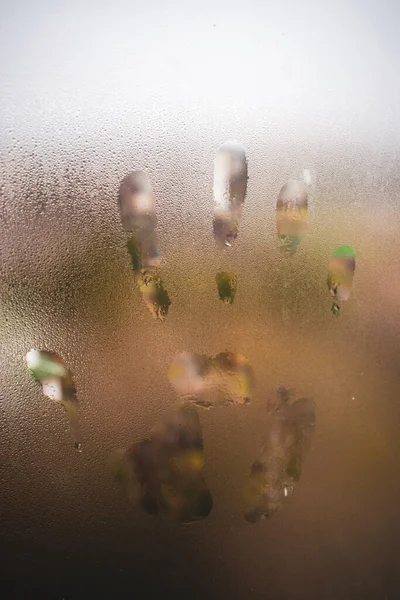 Selective focus of hand mark on glass condensation window, Right handprint with raindrop on the window with blurred background.