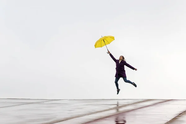 Mujer Saltando Horizonte Con Paraguas Amarillo Día Lluvioso Copia Espacio — Foto de Stock