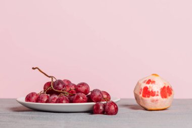 Bir demet üzüm ve pembe arka planda soyulmuş bir greyfurt. Metnin için kopyalama alanı olan minimalist natüralist yaşam.