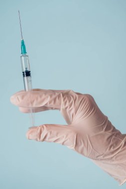 Tıbbi bir şırınga tutan beyaz tıbbi eldivenli bir elin yakın çekimi. Bağışıklık ve biyoteknolojik gelişim kavramı.