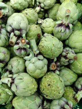 Enginar sebzeleri arka planda taze yeşil çiftçiler taze yiyecekler pazarlıyorlar sağlıklı yiyorlar. Alcachofa.