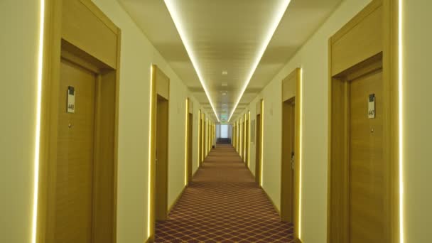 A long empty corridor in a hotel with many illuminated doors. hotel business suffers losses during pandemic — Stock Footage A long empty corridor in a hotel with many illuminated doors. hotel business suffers losses during pandemic Stock Video