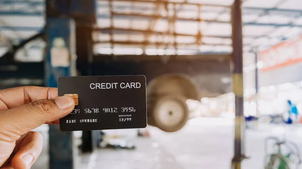 Hand holding a  credit cards at auto repair shop