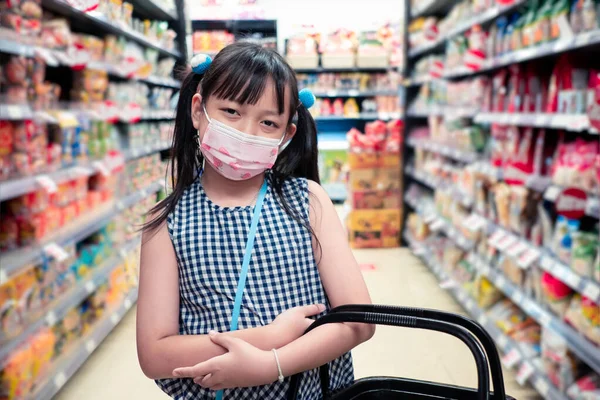 アジアの女の子身に着けています顔マスクと立ってでザスーパーマーケット — ストック写真