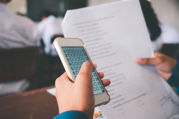 Exam by students doing educational test with using smartphone