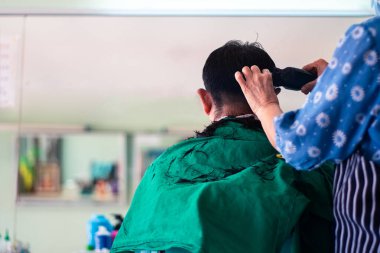 Kuaförde saç kesen bir adamın arkasında.