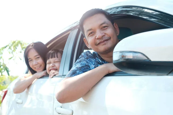 Happy asian family sitting in the car looking out windows