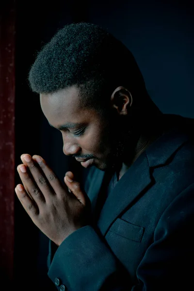 Afrikalı adam karanlık odada Tanrı için dua ediyor.