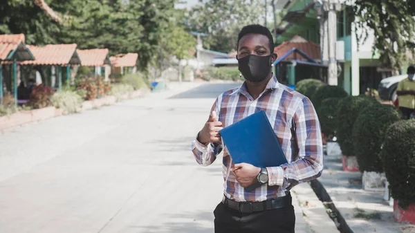 Portrait of african teacher in face mask standing outdoor at school