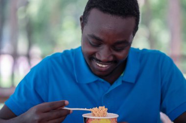 Afrikalı adam hazır şehriye çorbası içiyor.