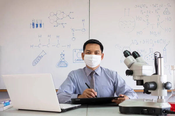 Science teacher wearing mask and   teaching in the classroom