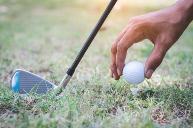 Golf oyuncusu golf sopasıyla golf topuna vuruyor.