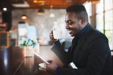 Afrikalı işadamı kahve dükkanında tablet bilgisayar kullanıyor