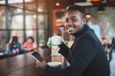 Afrikalı işadamı kahve dükkanında tablet bilgisayar kullanıyor