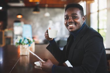 Afrikalı işadamı kahve dükkanında tablet bilgisayar kullanıyor