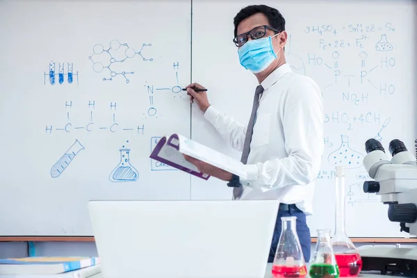 Chemistry science teacher wearing mask and   teaching in the classroom