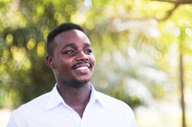 Gülümseyen Afrikalı beyaz gömlekli adam yeşil arka planda duruyor.