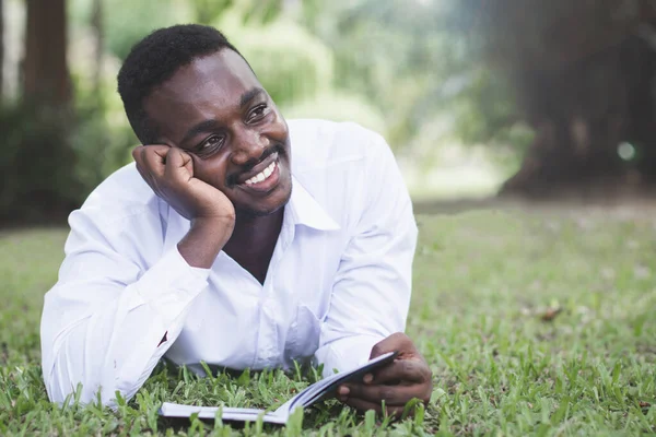 African man thinking and reading a book in the park.World book day Concept