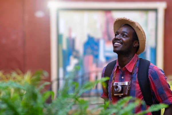 African tourist man on vacation smiling happy using vintage camera at the city